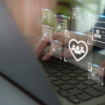 person typing on a computer with an icon of a heart with a monitor line through it