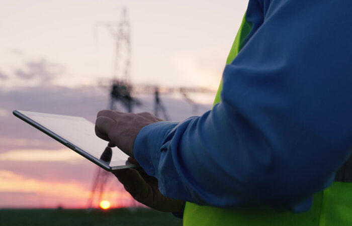 Man wearing saftey vest using tablet computer, with as sunset in the background