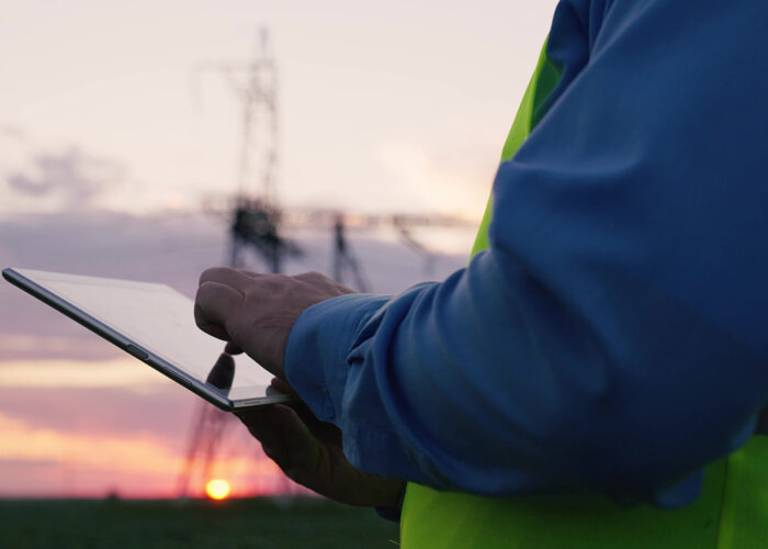 Man wearing saftey vest using tablet computer, with as sunset in the background