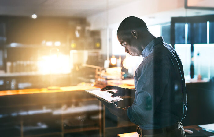 Man standing in office looking at tablet