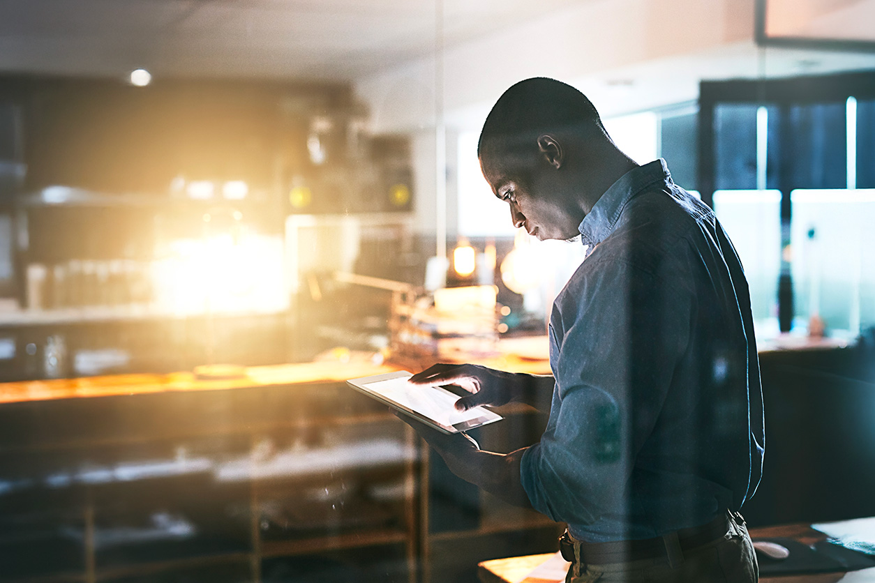 Man standing in office looking at tablet