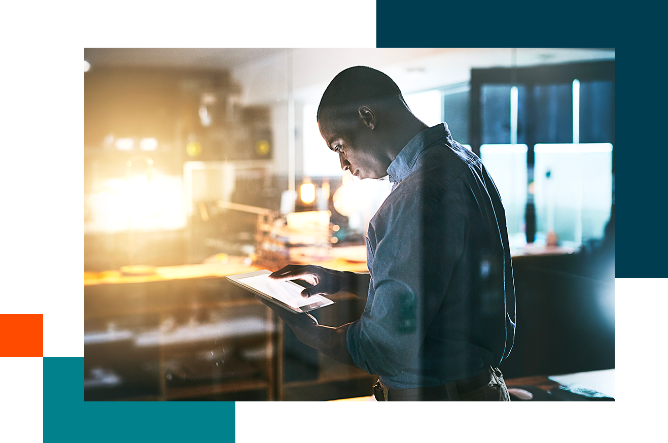 Man standing in office looking at tablet