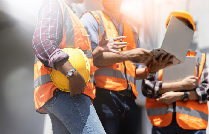 Construction workers in safety vests and helmets discussing plans.
