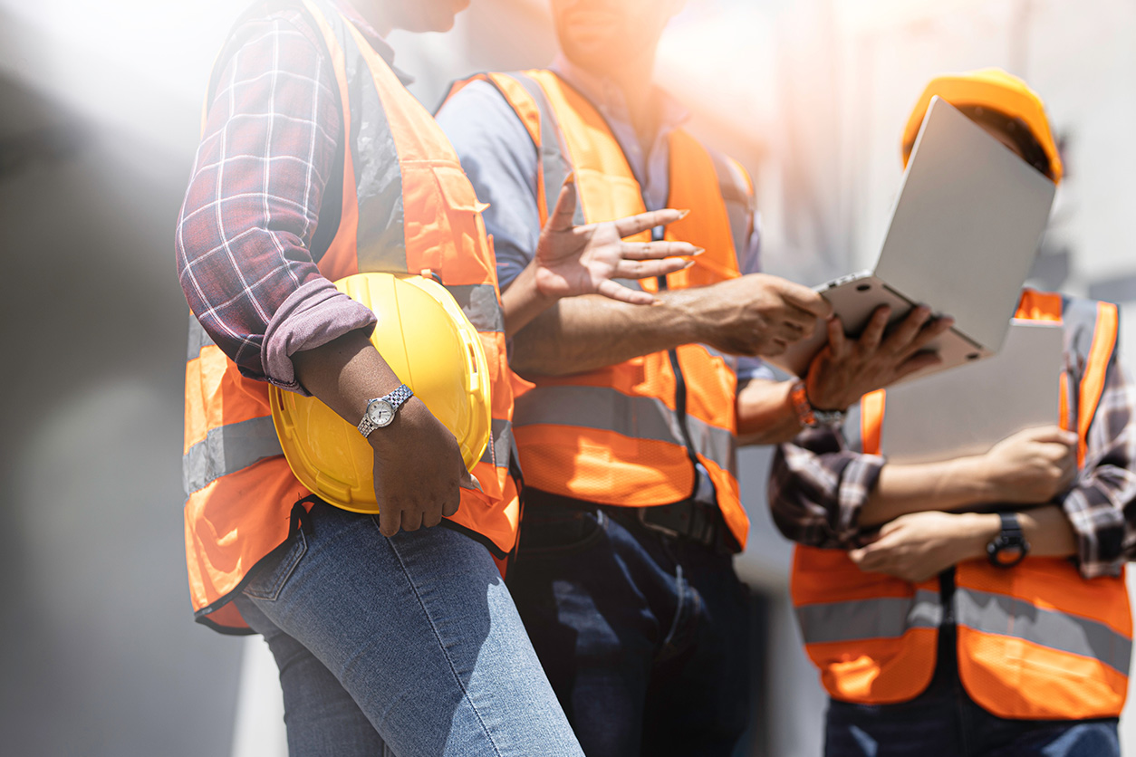Construction workers in safety vests and helmets discussing plans.