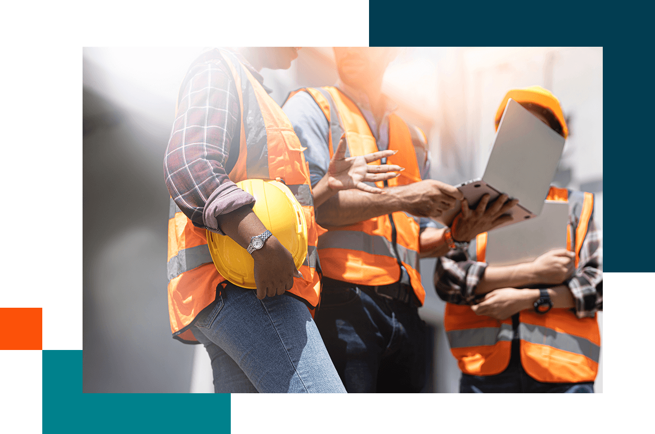 Construction workers in safety vests and helmets discussing plans.