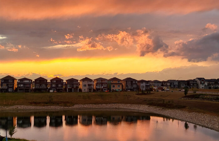 Row of houses with lake infront and a beautiful sunset sky