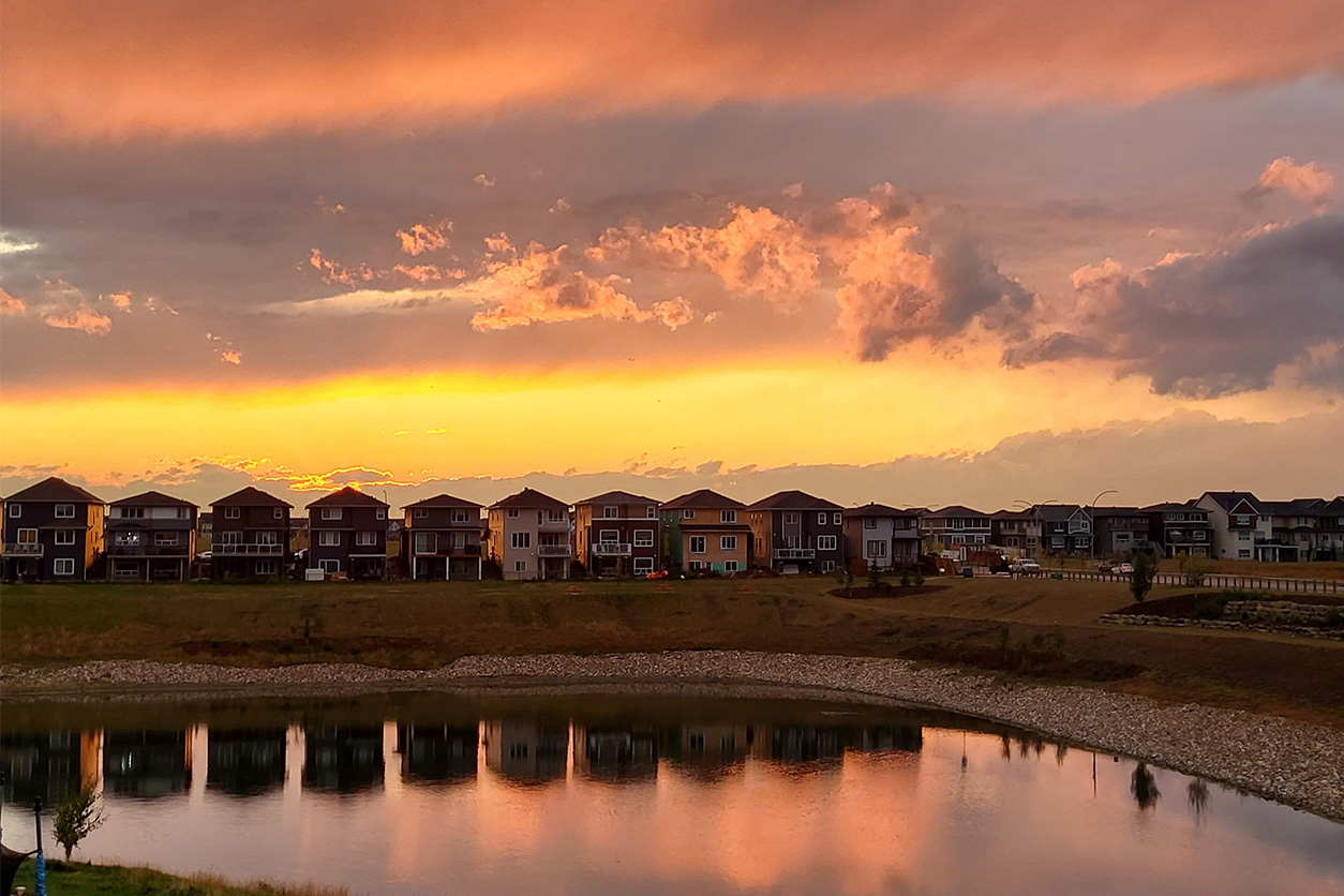 Row of houses with lake infront and a beautiful sunset sky
